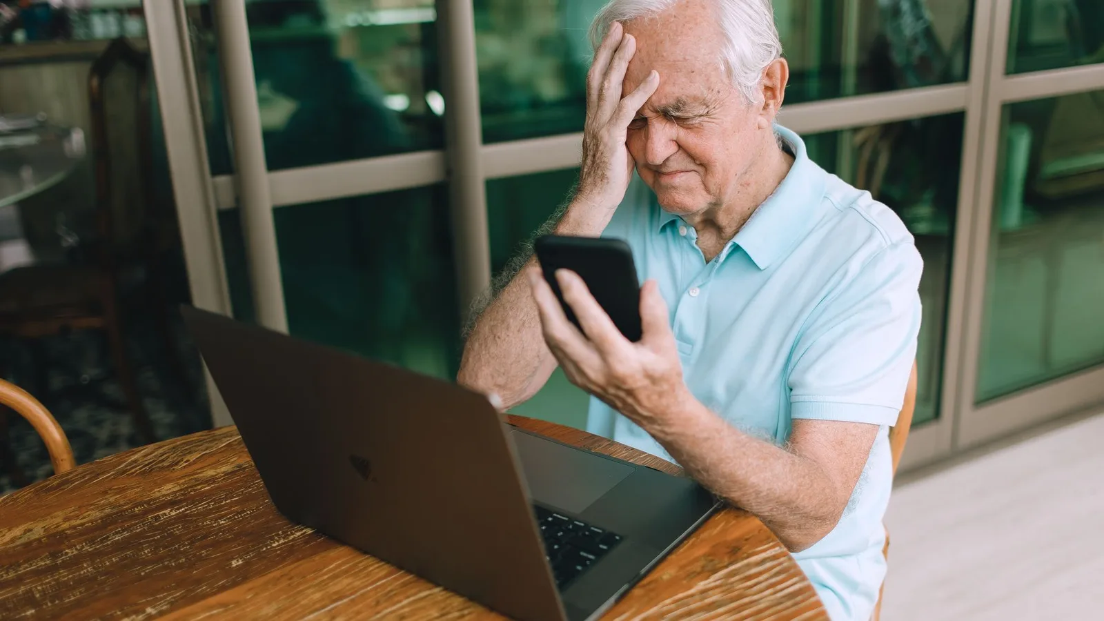 Pessoa idosa confusa ao usar laptop olhando anúncios de aparelhos auditivos online, com expressão de dúvida