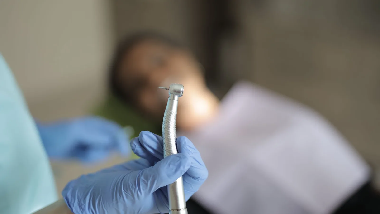 Dentista com protetor auricular em consultório odontológico, atento ao ruído de equipamentos