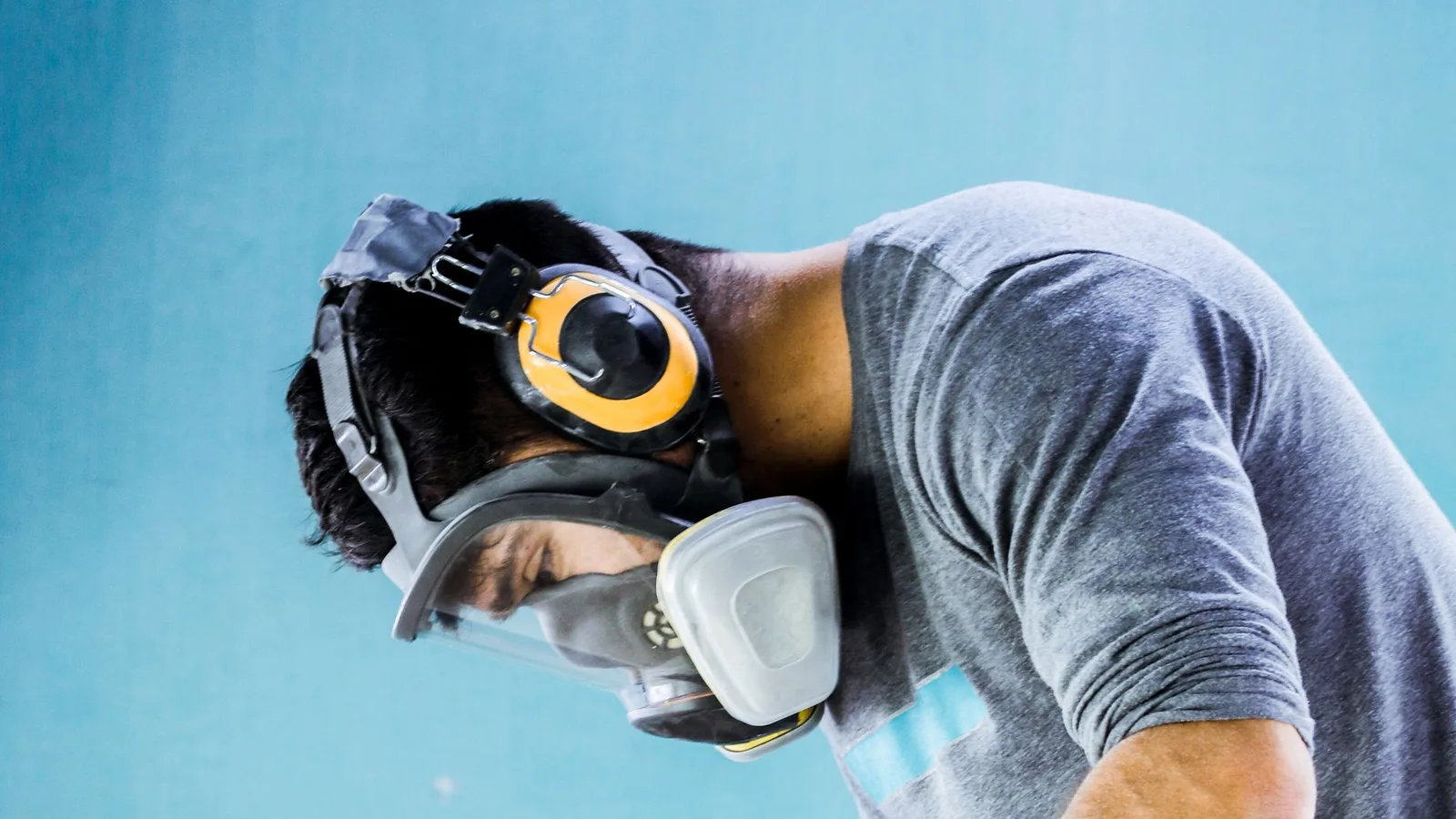 Trabalhador usando protetor auricular em ambiente industrial, com foco na proteção auditiva e prevenção de perda auditiva ocupacional.
