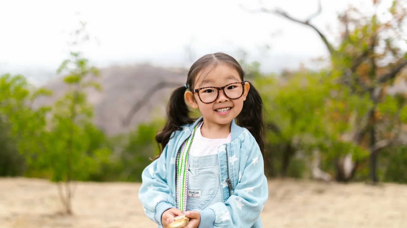 Menina sorridente usando óculos de grau novos ao ar livre